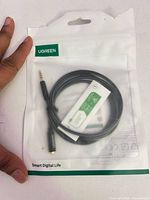 Front of retail pouch showing coiled black braided cable and UGREEN branding