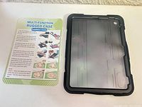 Front frame of black rugged tablet case beside installation guide card