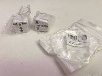 Two packaged white travel plug adapters and an empty bag shown