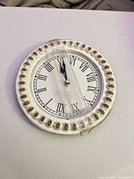Front view showing clock face, Roman numerals, beaded rim