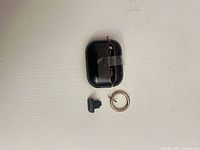 Front view of black wireless earbud charging case with keyring and silicone plug
