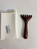 Wooden massage rake beside its white box