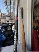 Black and natural wood baseball bats leaning against wall