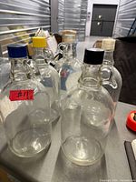 Five vintage clear glass jugs with colored tops grouped on table