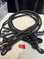 Six black bungee cords coiled together showing hooks