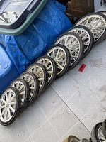 Eight identical white plastic spoke wheels with black tires arranged in a row