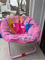 Overall view of the pink Disney Princess folding saucer chair on porch