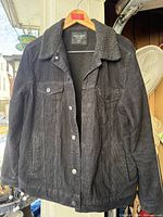 Front view of black corduroy sherpa-lined jacket on hanger