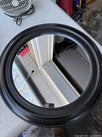 Round wall mirror with black frame shown from front to display condition and design