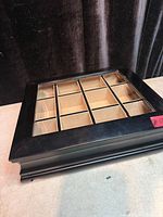 Closed wood watch case showing glass top and 12 interior sections