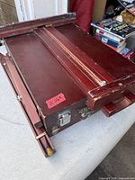 Closed wooden box easel showing latches, slide-out drawer, and canvas holder rail