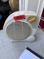 Front view of heater showing grille, control knob, power lights, brand name