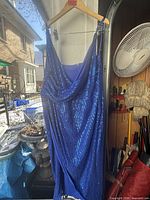 Front view of blue sequined evening gown hanging on hanger