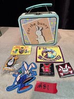 Group shot showing Pat the Bunny lunchbox, packaged pin, packaged button, and three patches