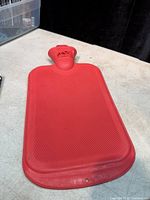 Full view of red rubber hot water bottle front side