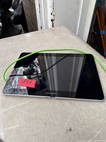 Front view of Samsung tablet with green USB cable on tabletop