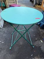 Table unfolded, showing round top, X-frame legs, teal finish