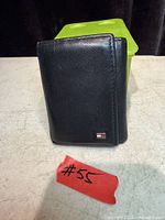 Closed black leather wallet front showing Tommy Hilfiger flag logo