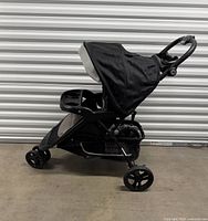 Left side view of Baby Trend stroller showing three-wheel design, canopy, child tray and basket