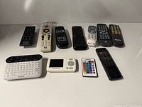 Group shot of all eleven remotes laid out on white surface