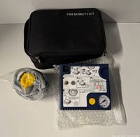 Overall lot showing tire mobility kit case, compressor unit and neck pump exerciser package