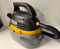 Left three-quarter view showing overall vacuum body, hose, latch and handle