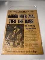 Front page with headline “Aaron Hits 714, Ties The Babe” in plastic sleeve