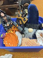 Bin containing witch figure, glittered haunted house, plush gnome, ceramic pumpkin bowl and seasonal towels