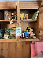 Wide view of shelves holding books, comics, Mickey Mouse toy, gloves and small items