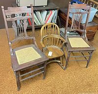Front view of two carved wood side chairs with cane seats and one child's spindle rocking chair