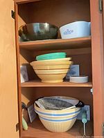 Cabinet view of entire lot showing nested bowls, CorningWare dish, saucers and utensils