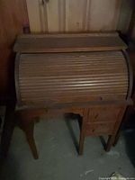 Front view of brown wood roll-top desk, tambour closed, showing left side drawers