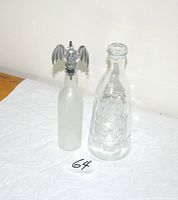 Two bottles side by side, one frosted with bat pourer, one clear embossed