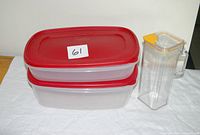 Two stacked Rubbermaid containers with red lids beside Komax clear container