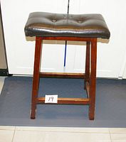 Front view of bar stool showing wood frame and leather seat