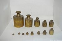 All thirteen brass weights arranged by size