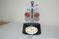 Front view showing clock face, red lights and crossing sign