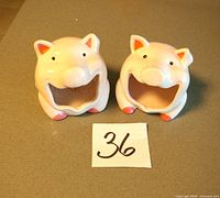 Front view of both pink ceramic pig sponge holders