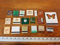 Full lot of 18 matchbooks in two rows with ruler for scale
