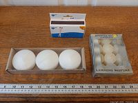 Lot overview showing matches box, three disc candles in tray, pack of six votives with ruler for scale