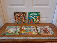 All five Berenstain Bears books laid out on table with ruler for scale