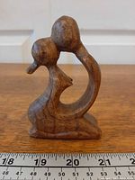 Front view of wooden kissing couple sculpture with ruler for scale