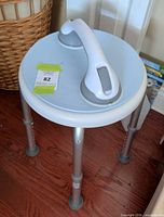 Full view of round shower stool with grab bar resting on seat