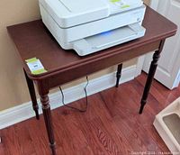 Front angled view of dark brown wooden side table with turned legs