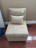 Front view of beige armless chair with pillow