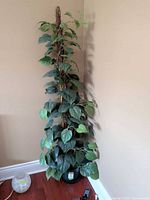 Full view of artificial plant in corner, showing height and pot