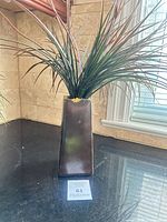 Front view of artificial plant in brown tapered vase
