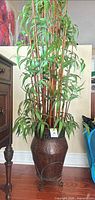 Full view of faux bamboo plant in metal pot on stand