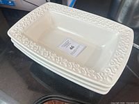 Three stacked white ceramic platters showing top view and border detail