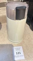 Full view of white electric coffee grinder with lid closed